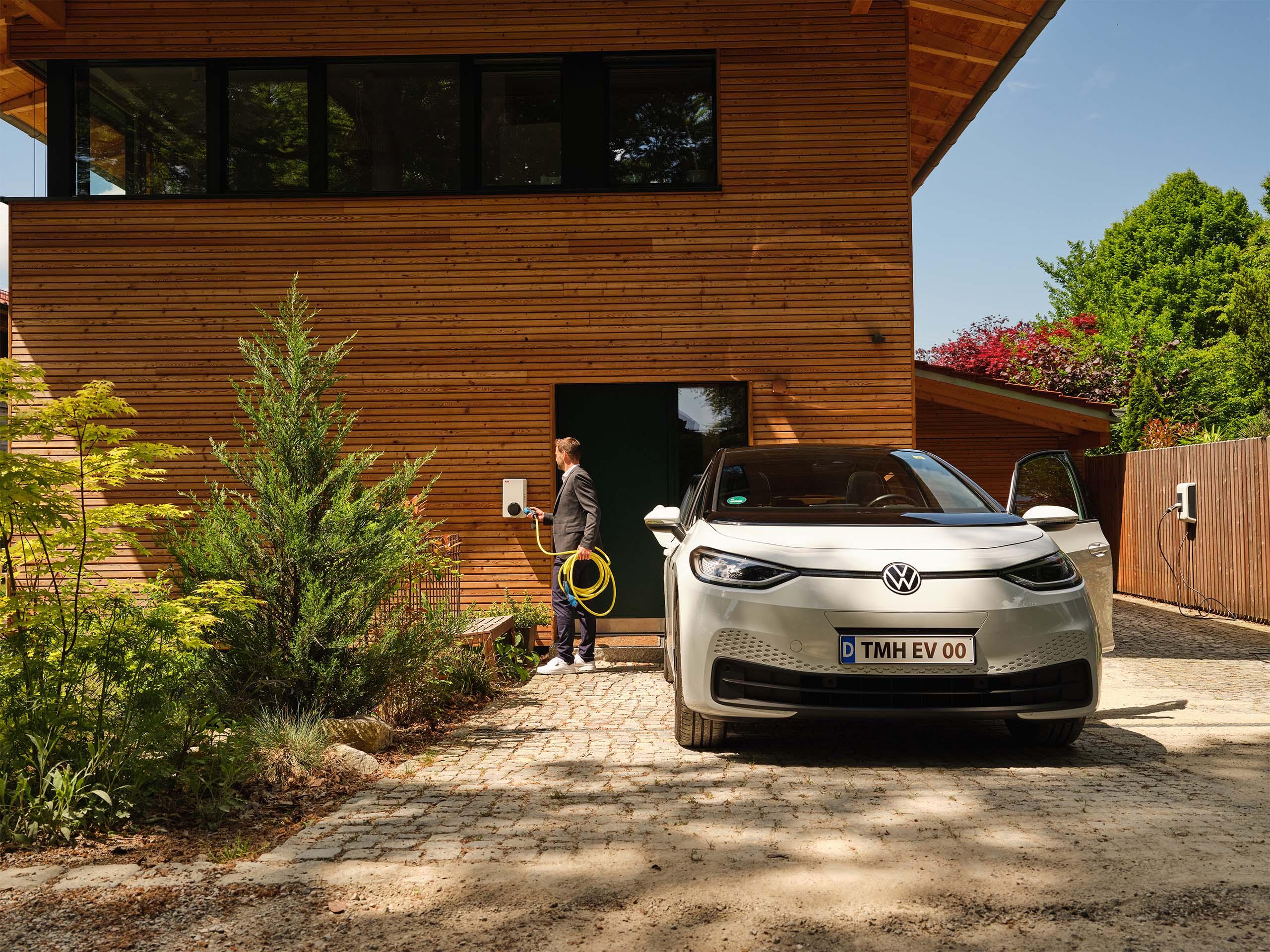 Mann lädt E-Auto in Einfahrt an Wallbox
